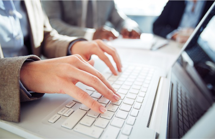 Mani che digitano sulla tastiera di un computer portatile durante una riunione di lavoro